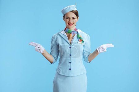 Photo for Happy elegant air hostess woman isolated on blue background in blue uniform gesturing. - Royalty Free Image