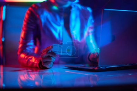 Photo for Neon metaverse futuristic concept. Closeup on woman with laptop and credit card in office. - Royalty Free Image