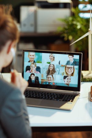 Photo for Seen from behind modern woman with laptop having webcam meeting in modern office. - Royalty Free Image