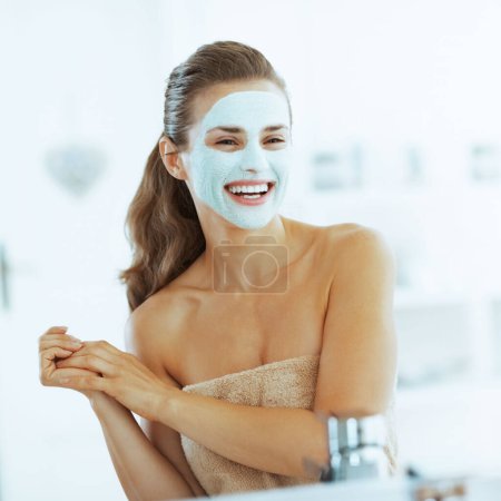 Foto de Joven sonriente con máscara cosmética en la cara - Imagen libre de derechos