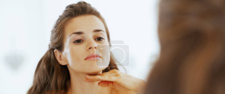 Photo for Young woman examining facial skin condition - Royalty Free Image