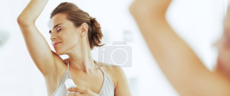 Photo for Woman enjoying freshness after applying roller deodorant on underarm - Royalty Free Image