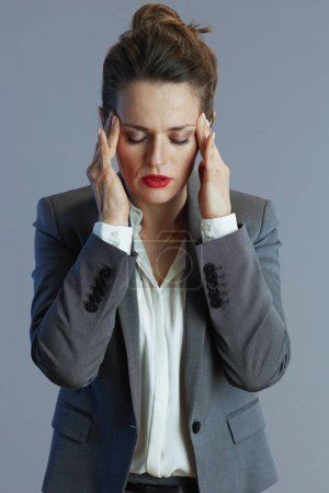 Foto de Mujer de negocios joven estresada en traje gris contra fondo gris. - Imagen libre de derechos