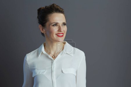 Foto de Sonriente mujer de negocios moderna de mediana edad en blusa blanca mirando el espacio de copia aislado en gris. - Imagen libre de derechos