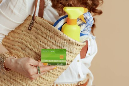 Photo for Beach vacation. Closeup on woman isolated on beige background with credit card and straw bag. - Royalty Free Image
