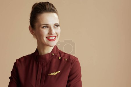 Photo for Happy stylish female air hostess against beige background looking at copy space. - Royalty Free Image
