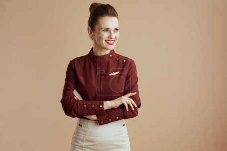Photo for Happy stylish female flight attendant on beige background looking at copy space. - Royalty Free Image