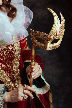 Foto de Primer plano de la reina medieval en vestido rojo con máscara veneciana y cuello blanco sobre fondo gris oscuro. - Imagen libre de derechos
