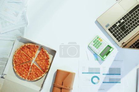 Téléchargez les photos : Vue supérieure de la pizza à la table avec documents et ordinateur portable. - en image libre de droit