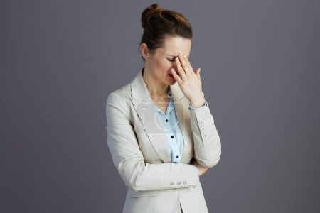 Foto de Mujer trabajadora elegante estresada en un traje de negocios ligero aislado en gris. - Imagen libre de derechos
