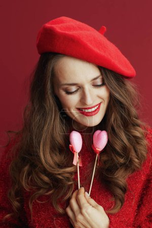 Photo for Happy Valentine. pensive modern woman in red sweater and beret with hearts on stick. - Royalty Free Image