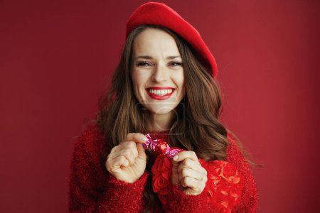 Foto de Feliz San Valentín. sonriente hembra moderna en suéter rojo y boina con caramelo. - Imagen libre de derechos