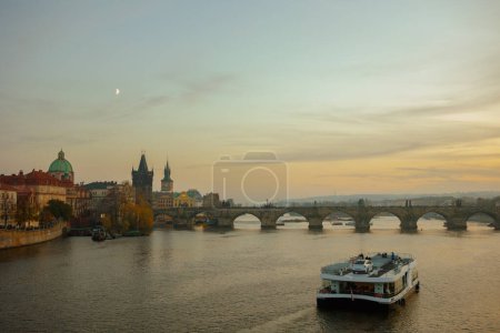 Téléchargez les photos : Paysage avec rivière Vltava, pont Charles et bateau au coucher du soleil en automne à Prague, République tchèque. - en image libre de droit