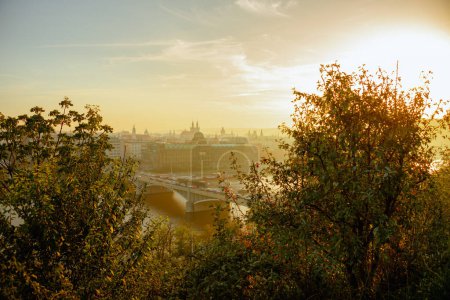 Téléchargez les photos : Paysage avec la rivière Vltava et l'église de notre dame avant tyn dans la soirée tiré à travers le feuillage en automne à Prague, République tchèque. - en image libre de droit