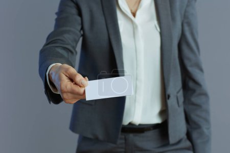 Foto de Primer plano de la mujer de negocios en traje gris con tarjeta de visita aislada sobre fondo gris. - Imagen libre de derechos
