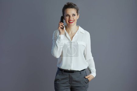 Photo for Smiling elegant woman worker in white blouse talking on old radio phone isolated on gray. - Royalty Free Image