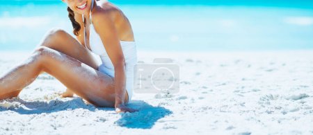 Téléchargez les photos : Souriant jeune femme assise sur la plage et regardant sur l'espace de copie - en image libre de droit