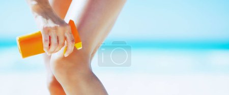 Téléchargez les photos : Gros plan sur la femme appliquant crème solaire sur la plage - en image libre de droit