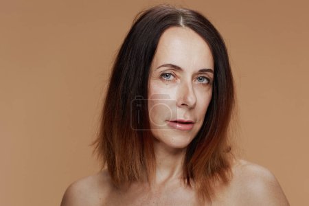 Téléchargez les photos : Portrait of modern 40 years old woman with short hair isolated on beige background. - en image libre de droit