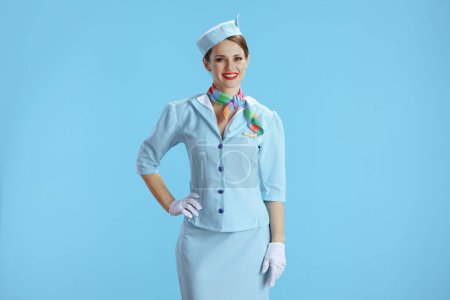 Téléchargez les photos : Heureuse hôtesse féminine élégante isolée sur fond bleu en uniforme bleu. - en image libre de droit