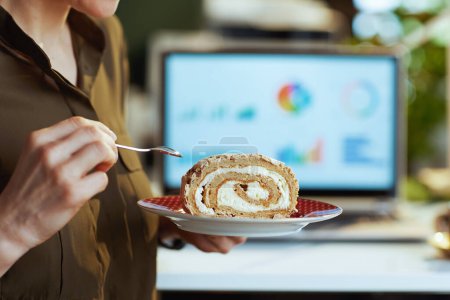 Photo for Closeup on modern female with laptop and piece of cake in modern office. - Royalty Free Image