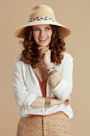 Photo for Beach vacation. smiling trendy 40 years old housewife in white blouse and shorts isolated on beige with summer hat. - Royalty Free Image