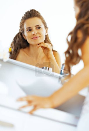Photo for Happy young woman checking facial skin condition - Royalty Free Image