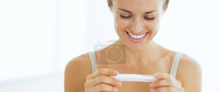 Foto de Mujer joven sonriente mirando en la prueba de embarazo - Imagen libre de derechos