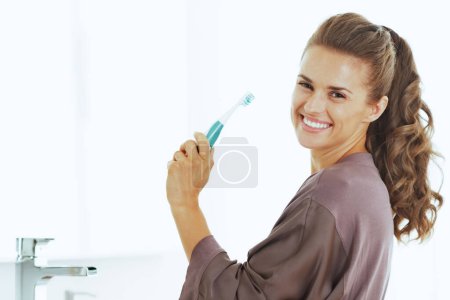 Téléchargez les photos : Femme souriante avec brosse à dents dans la salle de bain - en image libre de droit