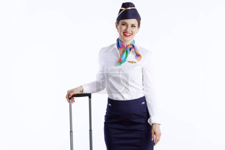 Foto de Elegante azafata femenina sonriente aislada sobre fondo blanco en uniforme con bolsa de viaje. - Imagen libre de derechos
