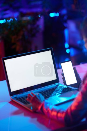 Photo for Closeup on modern female with laptop blank screen and smartphone blank screen in modern office. - Royalty Free Image