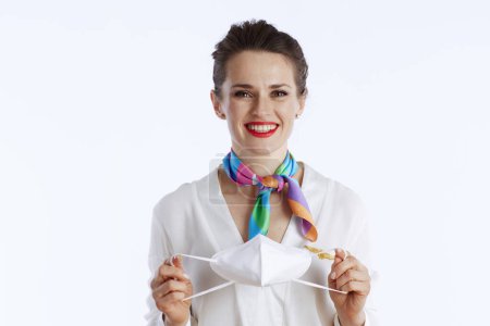 Photo for Happy stylish female stewardess against white background in uniform with ffp2 mask. - Royalty Free Image