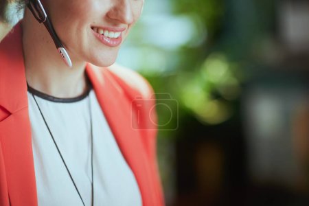 Photo for Sustainable workplace. Closeup on happy modern business woman in modern green office in a red jacket with headset. - Royalty Free Image
