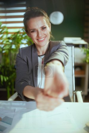 Téléchargez les photos : Un lieu de travail durable. heureuse femme d'affaires moderne dans le bureau vert moderne étirant les mains. - en image libre de droit