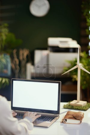 Foto de Visto desde atrás mujer moderna con pantalla en blanco portátil en la oficina moderna. - Imagen libre de derechos