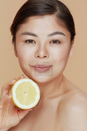 Téléchargez les photos : Moderne asiatique femelle avec citron sur fond beige. - en image libre de droit