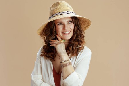 Téléchargez les photos : Vacances à la plage. heureuse élégante femme au foyer en chemisier blanc et short isolé sur fond beige avec chapeau d'été. - en image libre de droit