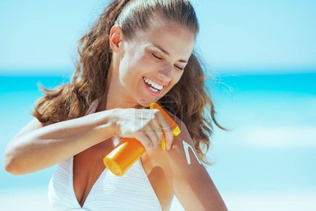 Photo for Happy young woman applying sun block creme - Royalty Free Image