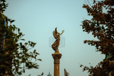 Téléchargez les photos : Paysage avec statue près de la salle de concert Rudolfinum dans la soirée filmé à travers le feuillage en automne à Prague, République tchèque. - en image libre de droit