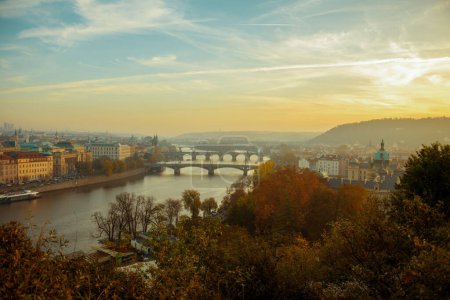 Téléchargez les photos : Paysage avec la rivière Vltava et le pont Charles au coucher du soleil a traversé le feuillage en automne à Prague, République tchèque. - en image libre de droit