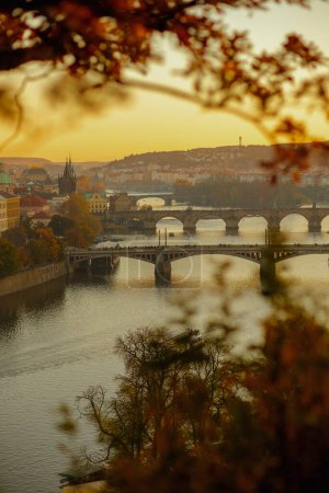 Foto de Paisaje con el río Moldava y el puente de Carlos por la noche atravesado por el follaje en otoño en Praga, República Checa. - Imagen libre de derechos