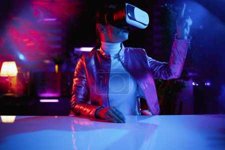 Photo for Neon metaverse futuristic concept. elegant female in virtual reality goggles using virtual reality technology in modern office. - Royalty Free Image