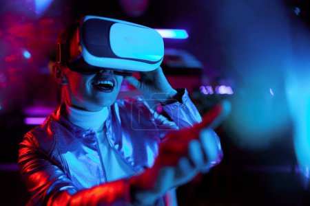 Téléchargez les photos : Neon metaverse concept futuriste. excité élégante femme d'âge moyen en réalité virtuelle lunettes modélisation en réalité virtuelle. - en image libre de droit
