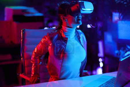 Téléchargez les photos : Neon metaverse concept futuriste. excité femelle élégante dans les lunettes de réalité virtuelle dans le bureau moderne. - en image libre de droit