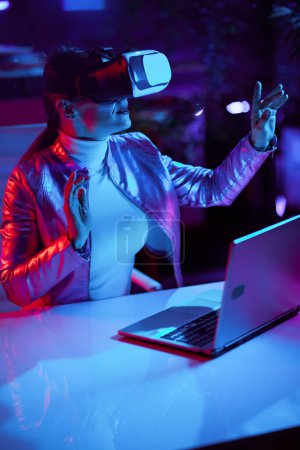 Foto de Concepto futurista neón metaverso. mujer moderna en gafas de realidad virtual utilizando la tecnología de realidad virtual en la oficina moderna. - Imagen libre de derechos