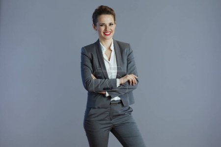 Téléchargez les photos : Heureux élégant d'âge moyen propriétaire de petite entreprise femme en costume gris sur fond gris. - en image libre de droit