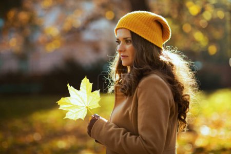 Foto de Hola otoño. mujer joven con abrigo marrón y sombrero amarillo con hojas amarillas de otoño al aire libre en la ciudad en otoño. - Imagen libre de derechos