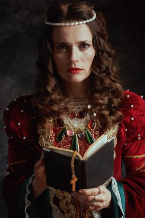Téléchargez les photos : Reine médiévale en robe rouge avec chapelet sur fond gris foncé. - en image libre de droit