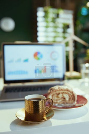 Photo for Mental health at work concept. Closeup on desk in modern office with piece of cake, cup of coffee and laptop. - Royalty Free Image