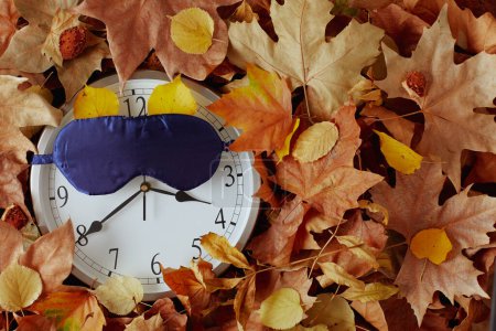 Foto de Fondo de otoño con reloj, máscara para dormir y hojas. - Imagen libre de derechos